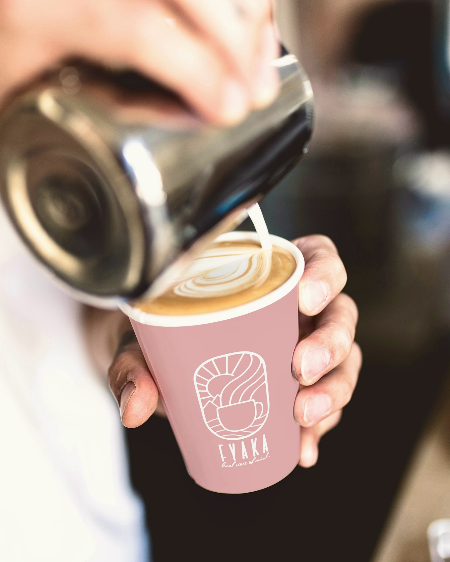 Latte art being poured into a pink Fyaka cup